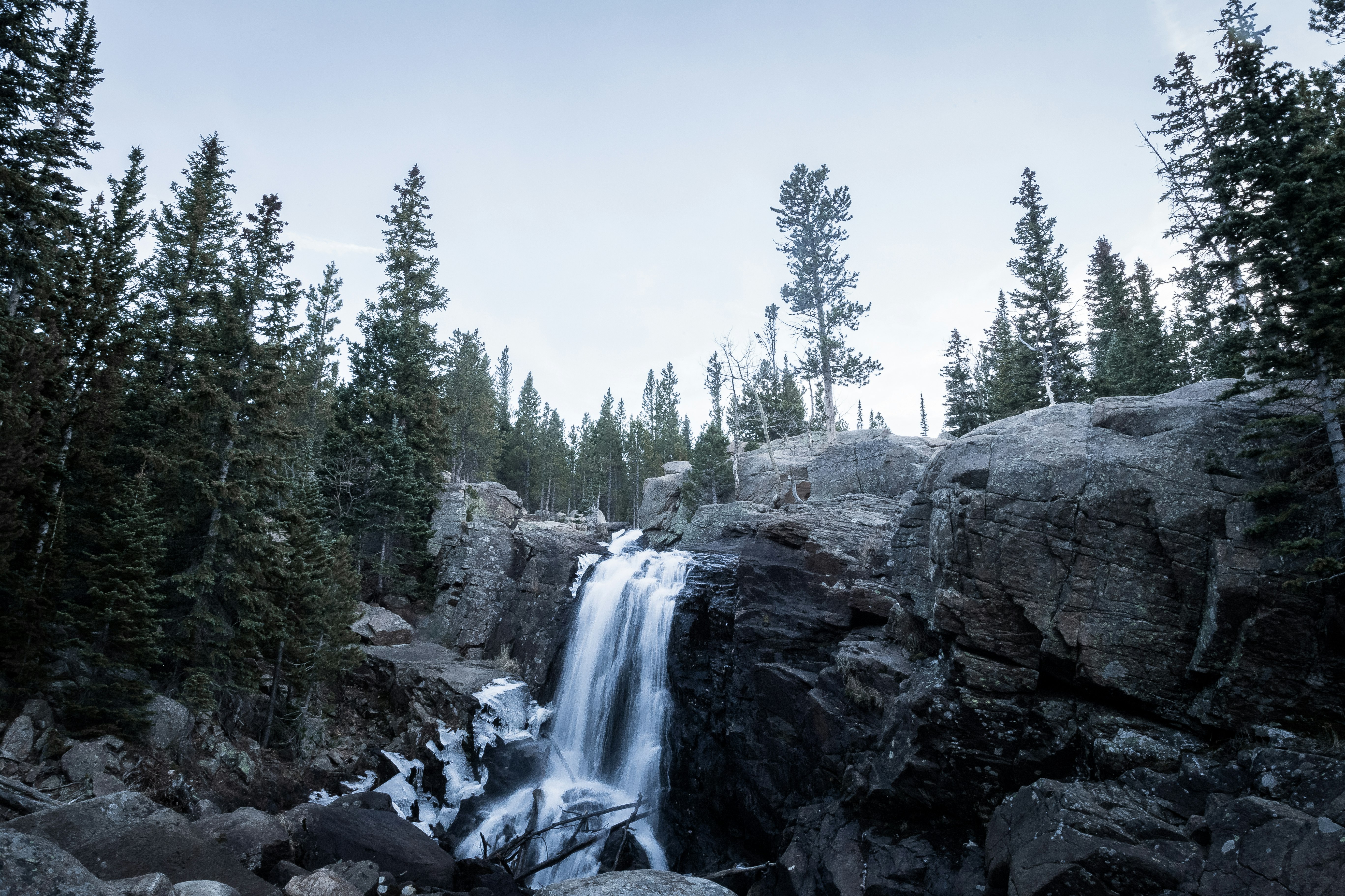 timelapse photography of waterfall surrounded by trees under blue sky at daytime